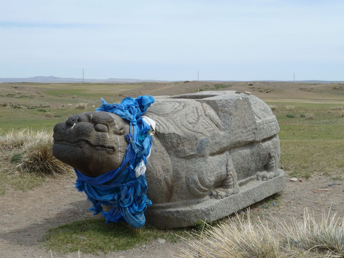 Ancient stone turtle in Kharkhorin draped in blue scarves